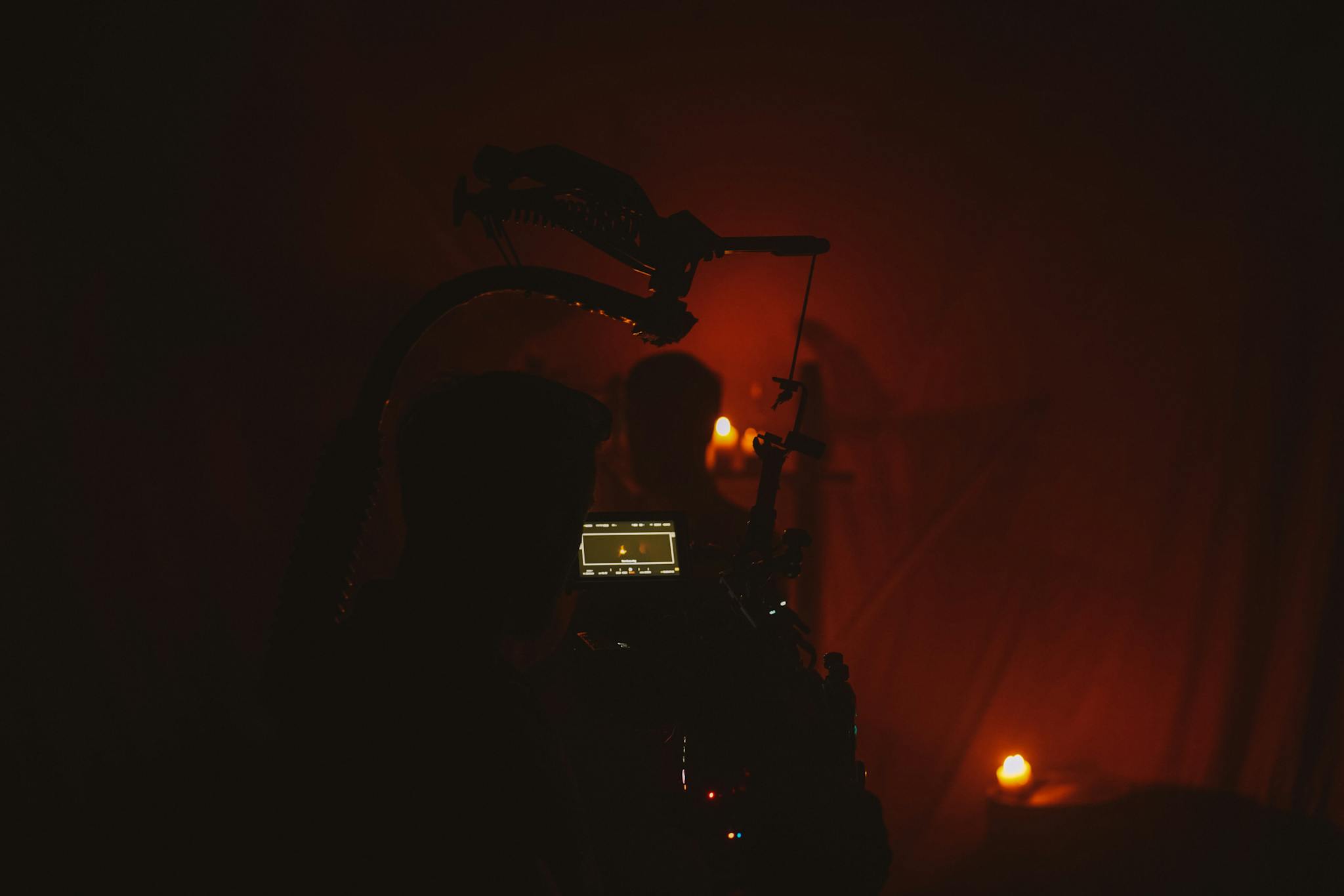 An atmospheric film set featuring a silhouetted cameraman filming by candlelight.