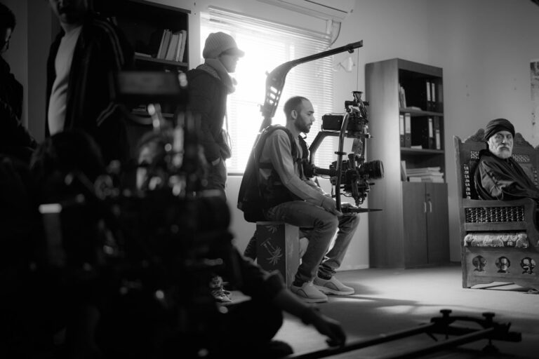 Black and white photo of a film crew working indoors with high-end camera equipment.